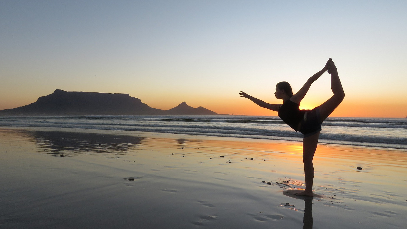 Frau macht Yoga vor einem Sonnenuntergang