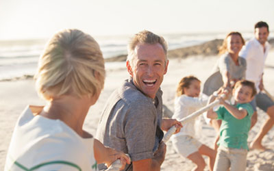 Eine lachende Familie beim Tauziehen am Strand.