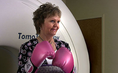 Frau mit Boxhandschuhen steht vor TomoTherapy Gerät