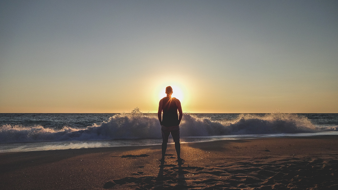 Achtung bei Bestrahlung oder Chemo und Sonne: Mann steht am Meer und blickt in den Sonnenuntergang