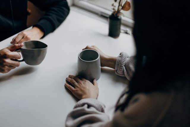 Krebs und Psyche: Zwei Menschen sitzen sich gegenüber und halten eine Tasse in der Hand