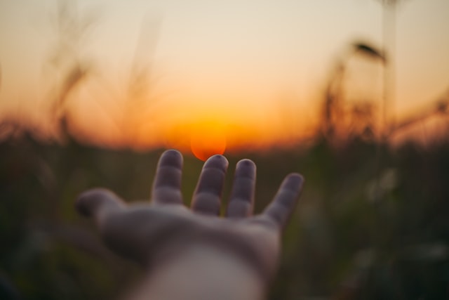 Psychoonkologische Therapie bei Krebs: Eine ausgestreckte Hand greift nach dem Sonnenuntergang
