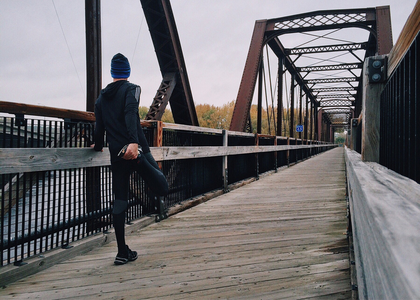Jogger dehnt seine Beinmuskeln auf einer Brücke