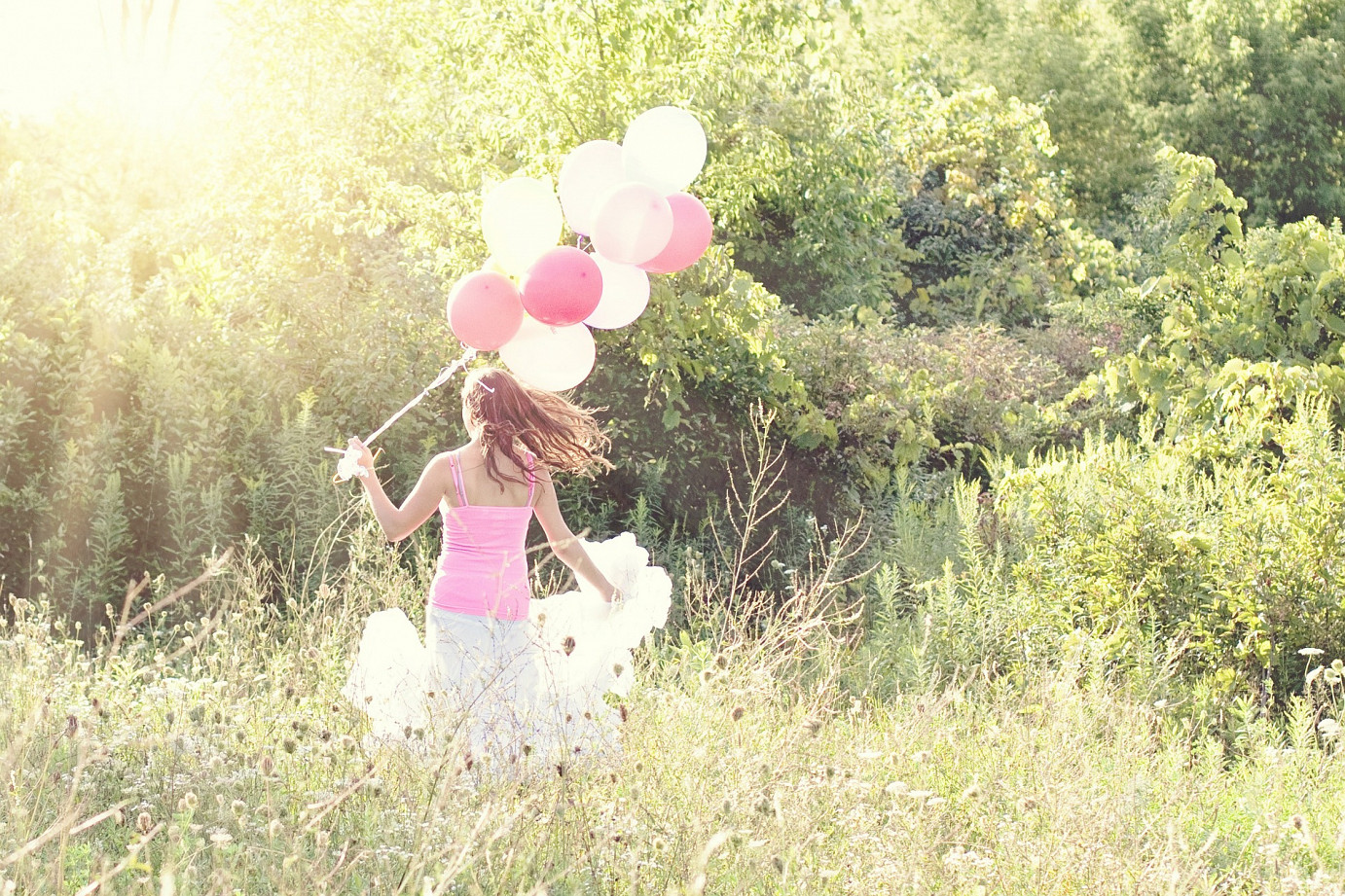 woman with pink balloons in field